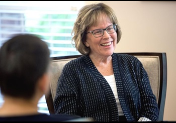 Dr Jane Fernandes, wearing a sweater, in a meeting with another person